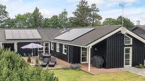 Ein modernes Haus mit überdachter Terrasse, Grillplatz und Solardach.