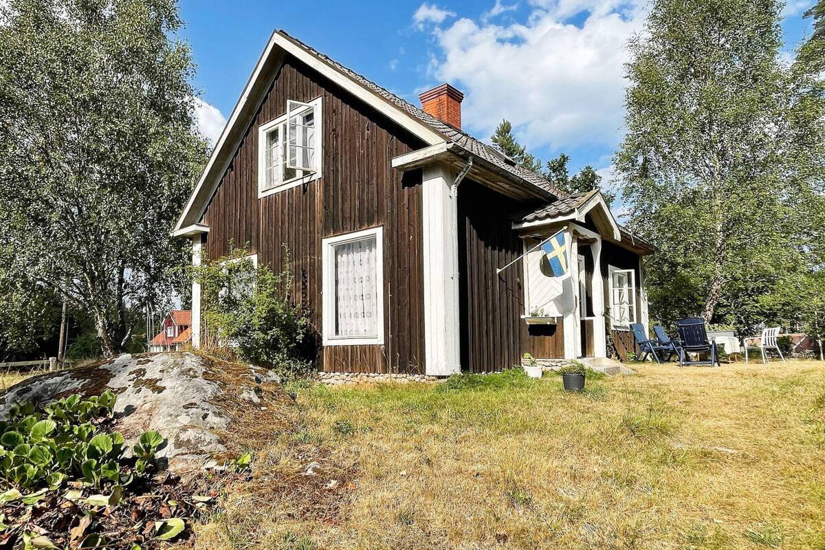 A wooden house with a gabled roof, a chimney, and a flag.
