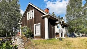 Ett trähus med ett sluttande tak, en skorsten och en flagga.