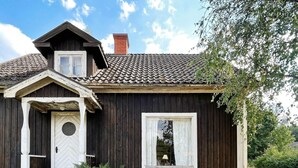 A wooden house with a gabled roof, a chimney, a front door, and a window. - 5 Person Holiday Home in Linneryd/kronobergs Lan (Linneryd)