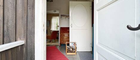 A hallway with a wooden door, a red carpet, and a small wooden chest.