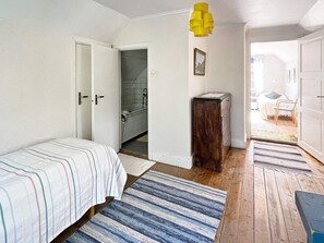 A bedroom with a bed, a wooden cabinet, a bathroom with a bathtub, and a hallway leading to another room. - 5 Person Holiday Home in Linneryd/kronobergs Lan (Linneryd)