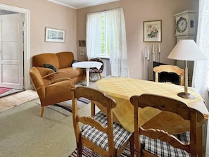 A cozy living room with a sofa, a dining table with chairs, a small table, and a clock on the wall. - 5 Person Holiday Home in Linneryd/kronobergs Lan (Linneryd)