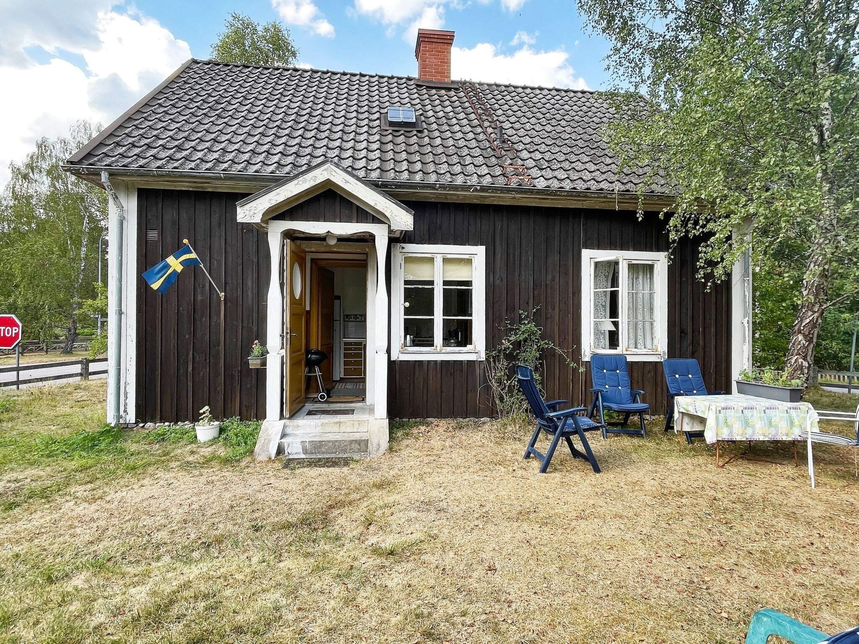 A wooden house with a dark roof, a flag, and outdoor seating.