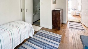 A bedroom with a bed, a wooden cabinet, a bathroom with a bathtub, and a hallway leading to another room. - 5 Person Holiday Home in Linneryd/kronobergs Lan (Linneryd)