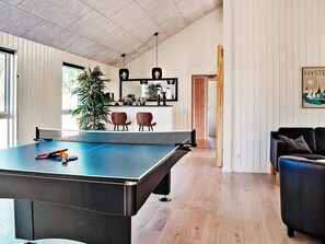 A spacious room with a ping pong table, a black sofa, and a wooden floor. - Holiday Home in Væggerløse (Vaeggerlose)