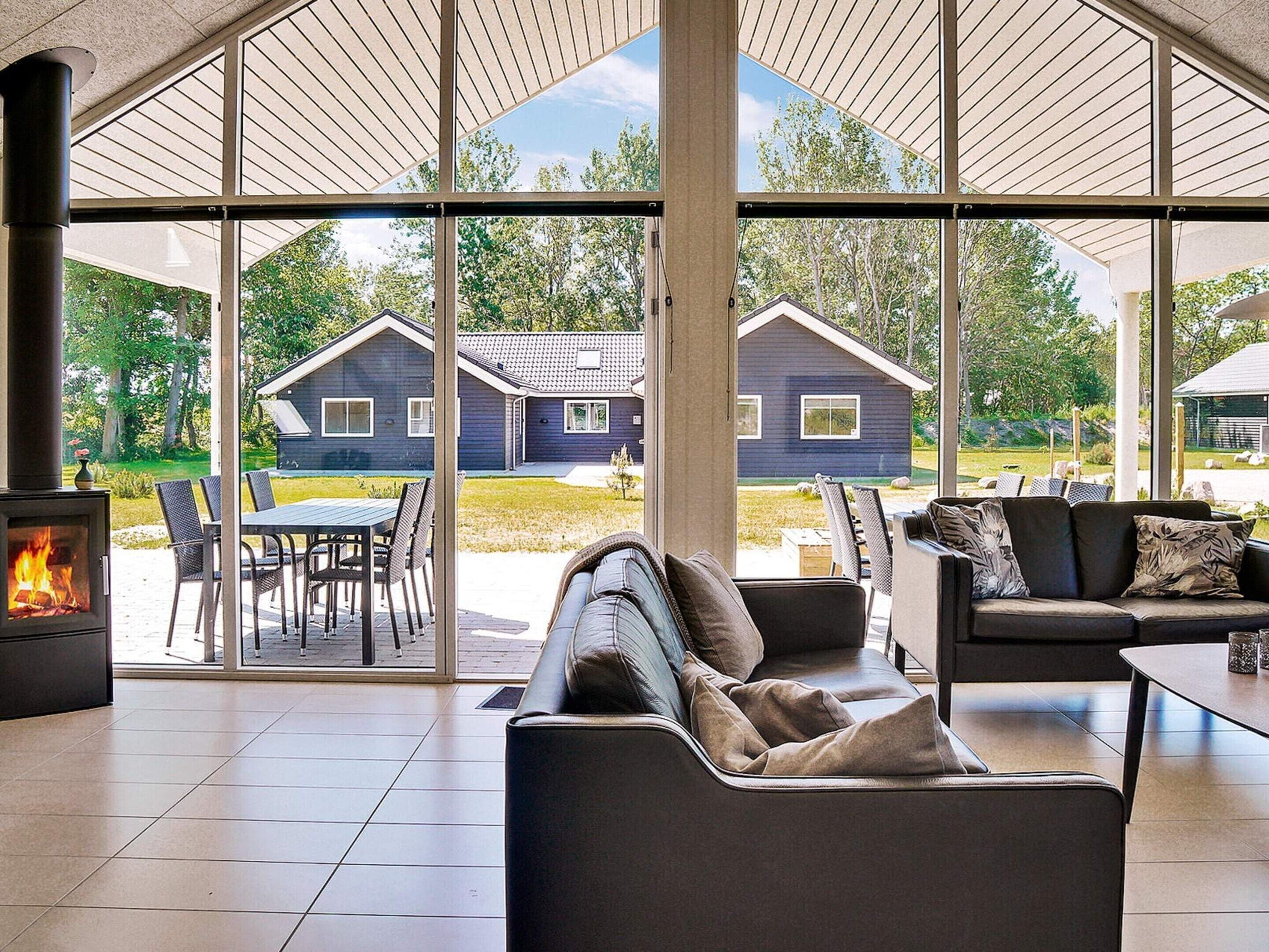 Un salon moderne doté d’une cheminée, de grandes fenêtres et offrant une vue sur l’extérieur.