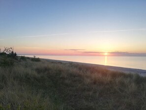 Une plage avec un coucher de soleil sur l’eau.