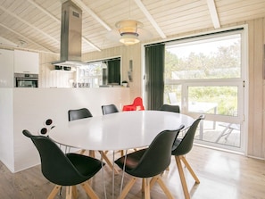 A modern kitchen with a central island, a dining area with a round table and chairs, and a large sliding glass door leading to an outdoor patio.