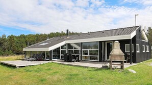 A modern house with a large patio, outdoor seating, and a stone fireplace. - Holiday Home in Løkken (Lokken)