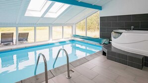 An indoor swimming pool with clear glass walls, a sunroof, and a spa area. - Holiday Home in Løkken (Lokken)