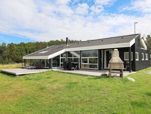 A modern house with a large patio, outdoor seating, and a stone fireplace.