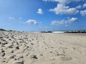 A wide sandy beach with footprints and rocks, leading to a rocky shoreline with waves. - Holiday Home in Gilleleje (Gilleleje)