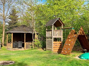 A wooden playhouse with a slide and a small deck area. - Holiday Home in Gilleleje (Gilleleje)