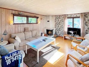 A cozy living room with a fireplace, a sofa, a coffee table, and a TV.
