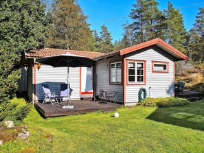 Une petite maison dotée d’un patio, d’un espace salon abrité et d’un jardin.