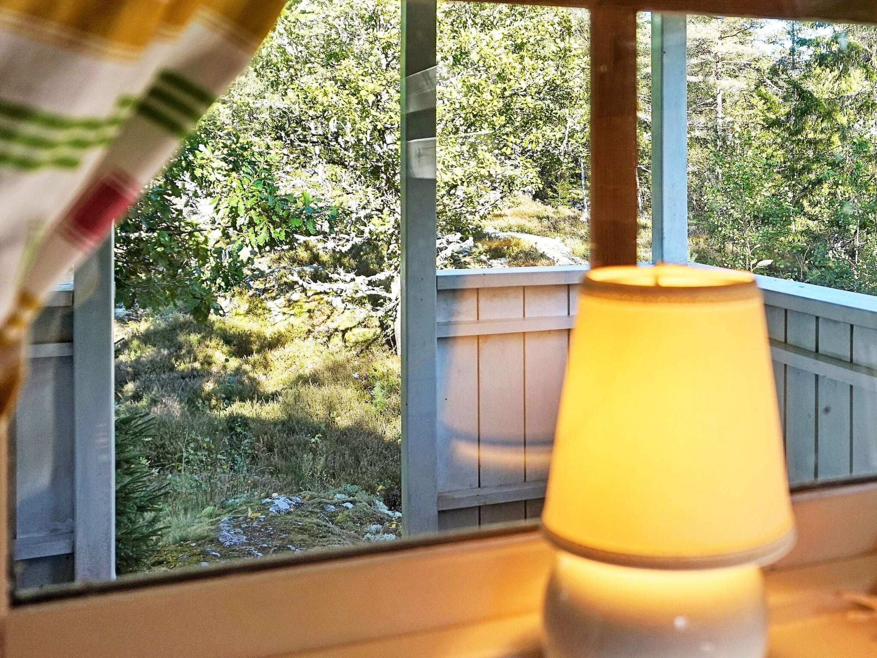 Een raam met uitzicht op een houten terras en een hek, met een lamp op de voorgrond.