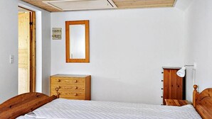 Une chambre à coucher avec un lit en bois, une commode, un miroir et une lampe de chevet.