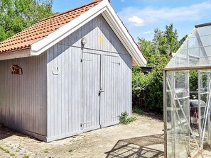 A wooden shed with a red-tiled roof and a glass greenhouse structure. - 4 Person Holiday Home in Store Fuglede (Store Fuglede)