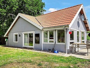 A single-story house with a sloped roof, a front porch, and a small deck. - 4 Person Holiday Home in Store Fuglede (Store Fuglede)