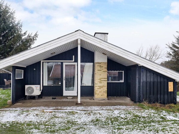 A single-story building with a dark exterior, a white door, and a small window. - 4 Star Holiday Home in Lokken (Lokken)
