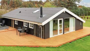 A modern house with a large deck, a chimney, and a sliding glass door.