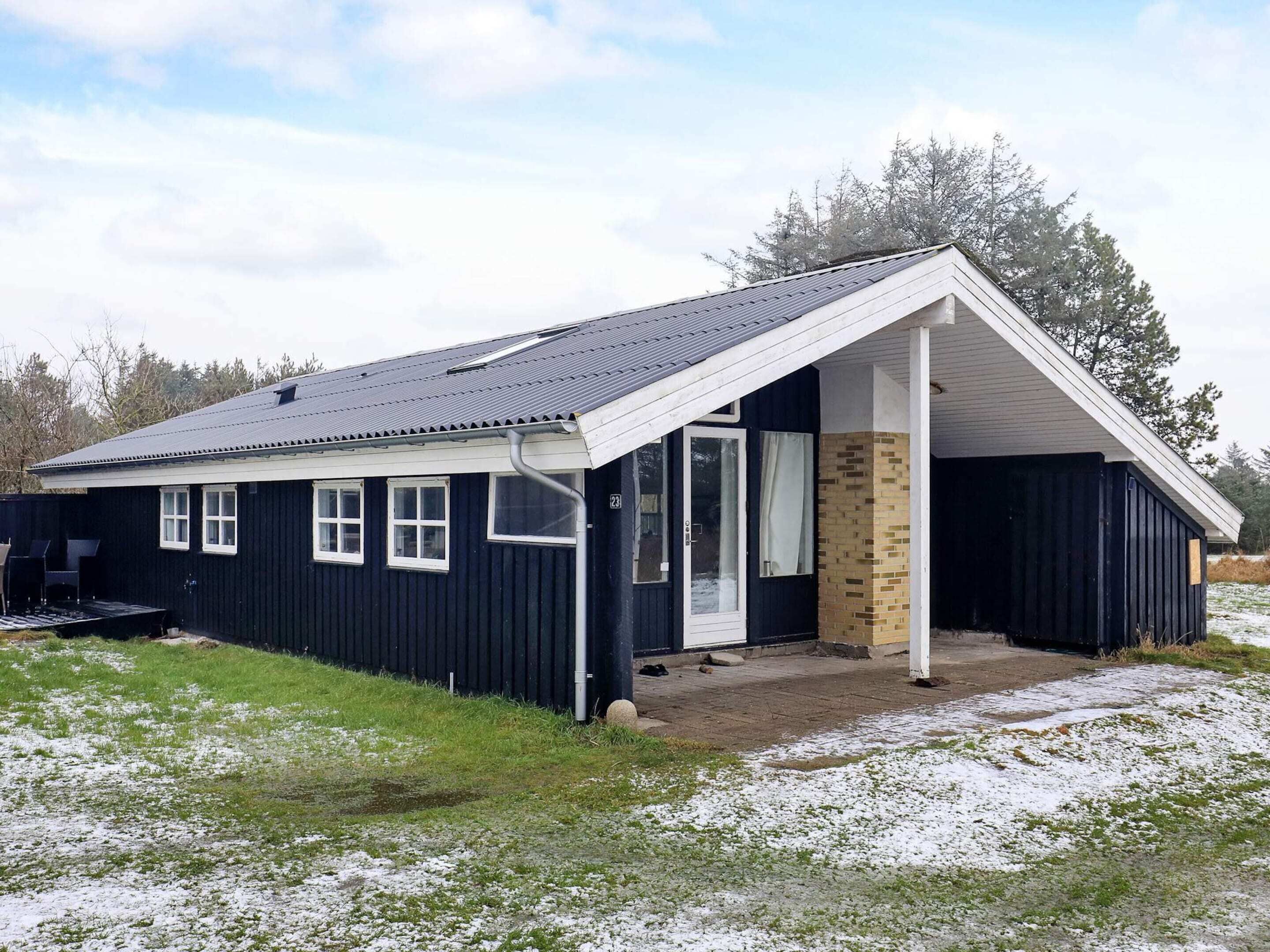 A single-story building with a dark exterior, a white porch, and a small attached garage.