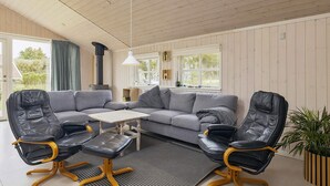 A modern living room with a sectional sofa, two leather chairs, a small table, and a potted plant. - 4 Star Holiday Home in Lokken (Lokken)