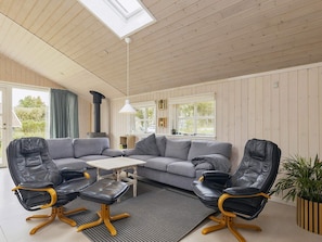 A modern living room with a sectional sofa, two leather chairs, a small table, and a potted plant. - 4 Star Holiday Home in Lokken (Lokken)