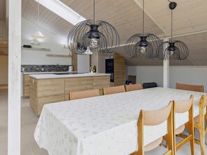 A modern kitchen with a central island, pendant lighting, and a dining area with a table and chairs.