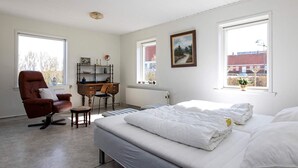 A bedroom with a bed, a desk, a chair, and a window with a view of buildings. - 7 Person Holiday Home in Lemvig (Lemvig)
