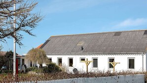 A white building with a grey roof, a white picket fence, and a red fire hydrant. - 7 Person Holiday Home in Lemvig (Lemvig)