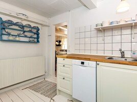 Cocina con armarios blancos, lavavajillas Bosch y encimera de madera.