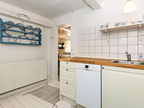 A kitchen with white cabinets, a Bosch dishwasher, and a wooden countertop. - Holiday Home in Marstal (Marstal)