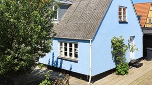 A blue house with a sloped roof, a window, and a tree in the foreground. - Holiday Home in Marstal (Marstal)