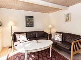 Una sala de estar con dos sofás de cuero marrón, una mesa redonda blanca y alfombras estampadas.