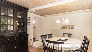 A dining area with a round table, black chairs, a dark wooden cabinet, and a white ceiling. - Holiday Home in Marstal (Marstal)