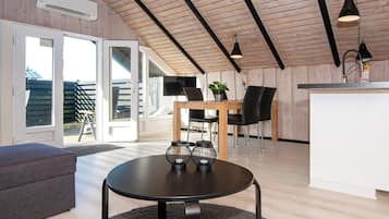 Un interior moderno con comedor, cocina y zona de estar con una mesa redonda.
