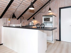 A modern kitchen with a central island, black pendant lights, and a microwave. - 4 Person Holiday Home in Hvide Sande (Hvide Sande)