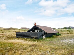 A small, single-story building with a sloped roof, a satellite dish, and a number '48' on the side. - 4 Person Holiday Home in Hvide Sande (Hvide Sande)