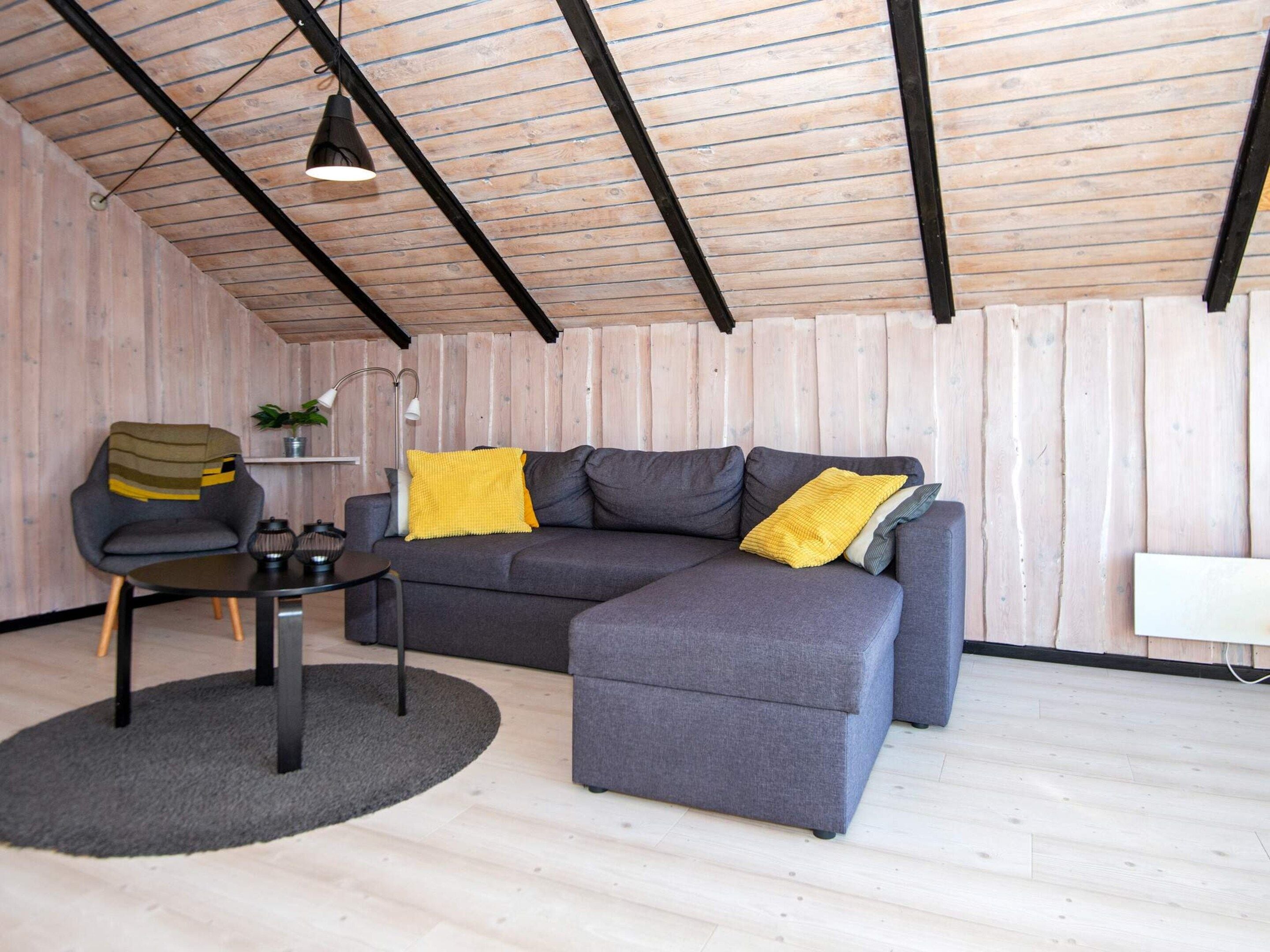 A modern living room with a grey sectional sofa, a round coffee table, and a small side table with a lamp.