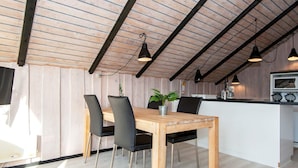 A dining area with a wooden table and chairs, a potted plant, and pendant lighting. - 4 Person Holiday Home in Hvide Sande (Hvide Sande)