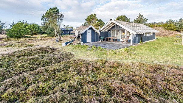 Une cabane rustique dotée d’une terrasse en bois, d’un petit porche et d’une grande fenêtre.