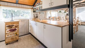 Une cuisine moderne avec des meubles en bois, un plan de travail en bois et une fenêtre qui laisse entrer la lumière naturelle.