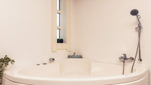 A bathroom with a bathtub, a shower, a window with a view, and a small plant.