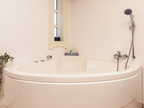 A bathroom with a bathtub, a shower, a window with a view, and a small plant. - Holiday Home in VÃ¦ggerlÃ¸se (Vaeggerlose)