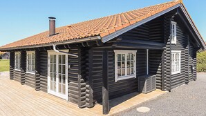 A log cabin with a tiled roof, a chimney, and a wooden deck.