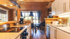 Une cuisine moderne dotée de plans de travail en granit, d’appareils électroménagers en acier inoxydable et de poutres en bois.