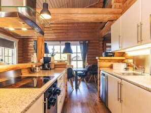 Une cuisine moderne dotée de plans de travail en granit, d’appareils électroménagers en acier inoxydable et de poutres en bois.