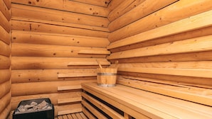 A wooden sauna with benches and a bucket.